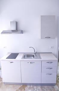 a white kitchen with a sink and a stove at Clambè in Palermo