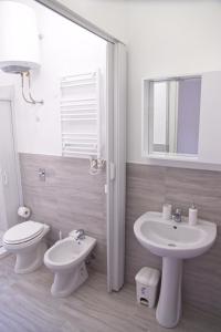 a white bathroom with a toilet and a sink at Clambè in Palermo