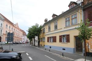 una strada con un edificio giallo sul lato della strada di Anne's House a Sibiu