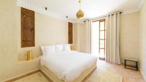 a bedroom with a white bed and a window at Chez Ichou in Aït Idaïr