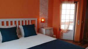 a bedroom with a bed with blue pillows and a window at Casa das Conchas in Ericeira