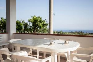 einen weißen Tisch und Stühle vor einem Fenster in der Unterkunft Villa Alice in Capo Vaticano