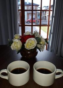 um vaso de flores e duas chávenas de café em Apartamento das Flores em Gramado