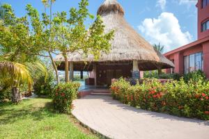 a building with a thatch roof and a garden at Selina Cancun Laguna Hotel Zone in Cancún