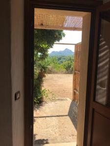 une porte ouverte avec vue sur un champ de terre dans l'établissement Li Casacci, à Arzachena