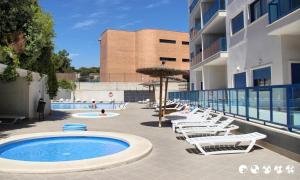 einen Pool mit Stühlen und Sonnenschirmen neben einem Gebäude in der Unterkunft Alicante Hills Beach & Golf in Alicante