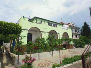 a green building with a fence in front of it at Apartmani Ana Novi V. - studio in Novi Vinodolski