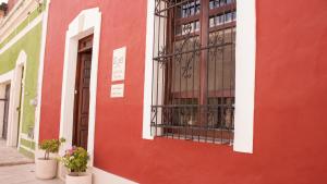 ein rotes und grünes Gebäude mit einem Fenster und Topfpflanzen in der Unterkunft Casa Italia Luxury Guest House - Adults Only in Mérida