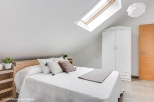 a white bedroom with a bed and a skylight at Apartamento Playa de Quenxe in Corcubión