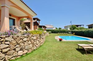 a backyard with a stone wall and a swimming pool at Le Dimore di Nettuno - Happy Rentals in Olbia
