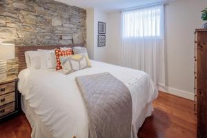 a bedroom with a white bed and a stone wall at The Hillside House - Downtown Kingston in Kingston