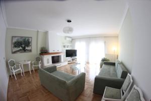 a living room with a couch and chairs and a tv at Cozy Penthouse in Thessaloniki