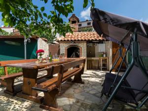 a wooden picnic table with an umbrella in a yard at Apartment Vita in Poreč