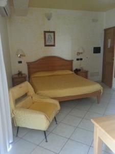 a bedroom with a bed and a chair at Hotel Mistef in Falerna