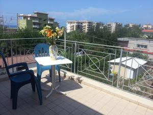 a table and chairs on a balcony with a vase of flowers at Hotel Mistef in Falerna