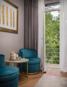 ein Wohnzimmer mit blauen Stühlen, einem Tisch und einem Fenster in der Unterkunft Five Elements Luxury Rooms in Split