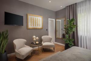 um quarto com 2 cadeiras, uma mesa e uma televisão em Five Elements Luxury Rooms em Split