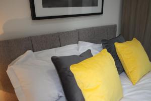 a bed with yellow and white pillows on it at Halifax House, Studio Apartment 207 in Halifax