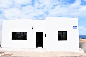 a white building with two windows and a door at Casa Los Lajares in Tinajo