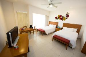 ein Hotelzimmer mit zwei Betten und einem Fernseher in der Unterkunft Ambiance Suites in Cancún