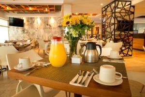 una mesa con un jarrón de flores y una jarra de zumo de naranja en Ambiance Suites en Cancún