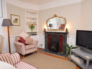 a living room with a fireplace and a television at Burton House Apartment in Lyme Regis