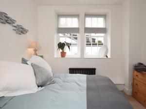 a white bedroom with a bed and a window at Burton House Apartment in Lyme Regis