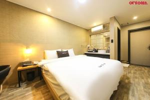 a bedroom with a large white bed and a desk at Ace Hotel in Tongyeong