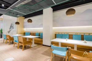 uma sala de jantar com mesas e cadeiras azuis em Atour Hotel Shangrao Central Square em Shangrao