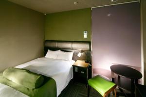 a hotel room with a bed and a stool at Hotel Quest Shimizu in Shizuoka