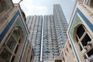 a tall apartment building in front of a large building at RedLiving Apartemen Saladdin Mansion - RAN Management in Depok
