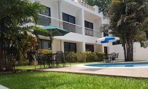 a hotel with tables and chairs next to a swimming pool at Hotel Holly in Mérida