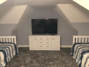 a room with two beds and a television on a dresser at Blackberry Bunkhouse in Ashford