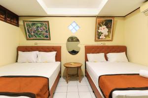 a room with two beds and a table at Downtown Monkey Forest Hostel in Ubud