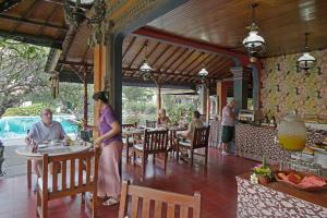 a group of people sitting at tables in a restaurant at Bumas Hotel in Sanur