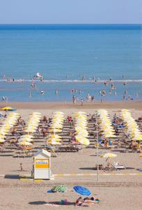 a group of people on a beach with umbrellas at Hotel Universal in Caorle