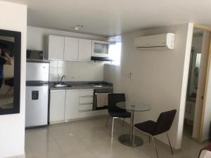 uma cozinha com armários brancos e uma mesa e cadeiras em Apartamento cómodo en la ciudad bonita em Bucaramanga
