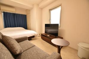 a hotel room with a bed and a couch and a tv at Randor Residence Tokyo Grand in Tokyo
