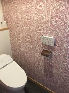 a bathroom with a toilet and a wall at Guesthouse Kazenowa in Asahi
