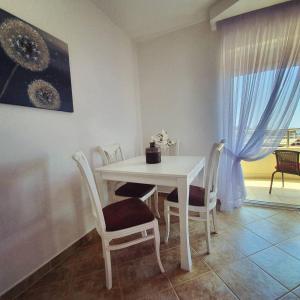 - une table et des chaises blanches dans une chambre avec fenêtre dans l'établissement Panorama Petrovac, à Petrovac na Moru