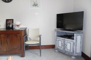 a television on a stand with a chair and a desk at Les Marguerites Aux Lotz in Thiers +5 photos