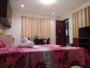 Un dormitorio con una cama rosa con un animal de peluche. en Lourdes Inn, en Manila