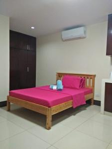 マニラにあるルルド インのベッドルーム1室(ピンクのシーツが備わる木製ベッド1台付)
