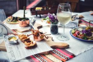 a table with a plate of food and a glass of wine at Zlatna ribka in Kokolyane