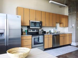 eine Küche mit Holzschränken und Küchengeräten aus Edelstahl in der Unterkunft City Loft w/ View of Gay St in Knoxville