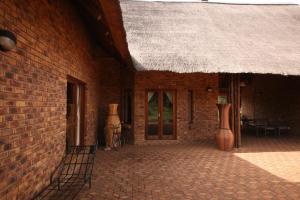 ein Backsteingebäude mit Strohdach und Terrasse in der Unterkunft Makhato Bush Lodge 109 in Bela-Bela