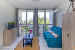 sala de estar con sofá azul y TV en Boucan Beach Joli studio vue mer à Boucan Canot, en Boucan Canot