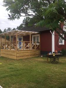 a house with a wooden deck and a table in the yard at Kolstigenhus in Fågelfors