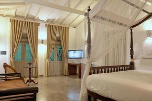 a bedroom with a canopy bed and a television at Era Beach in Unawatuna