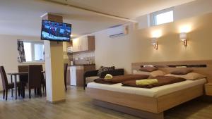 a living room with a bed and a television on a wall at Central Panzió Gyula in Gyula